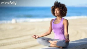 A woman sits cross-legged on the beach
