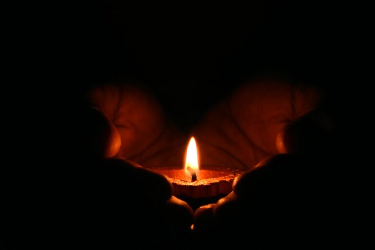 Pair of hands gently holding a glowing candle symbolizing comfort, healing, and remembrance for grief and bereavement online support group in Ohio.