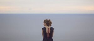 A woman stands on a cliff