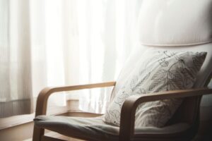 A cozy chair with a decorative pillow beside a bright window