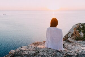 A woman sits on a rock