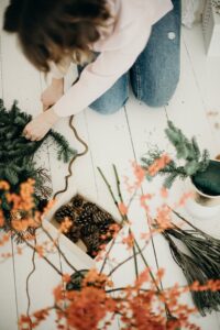 A woman carefully arranges a festive Christmas wreath on the floor