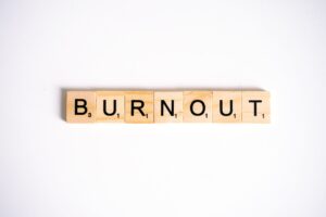 Scrabble tiles spelling the word "burnout" arranged on a wooden game board.