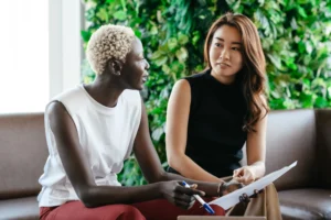 Two women sitting on a couch discussing job search strategies