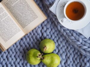 A cup of tea and two fresh pears placed on a blue blanket