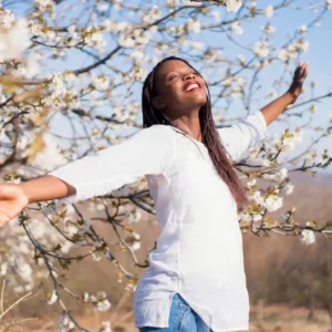 A woman poses in front of a flowering tree