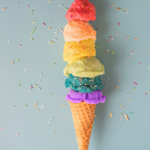 A vibrant rainbow ice cream cone topped with colorful sprinkles against a neutral background.