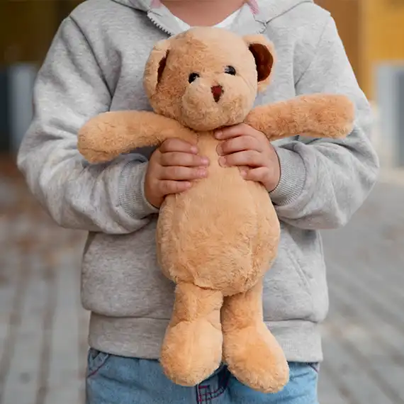 Young child clutching a teddy bear, symbolizing the need for comfort and emotional security.