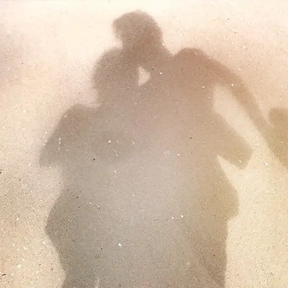 Shadows of two people embracing on the sand, symbolizing intimacy and emotional connection.