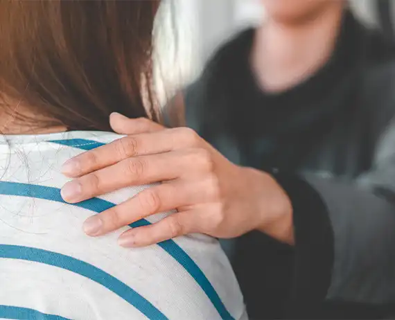 Close-up of a reassuring hand resting on a shoulder, symbolizing empathy and emotional support.