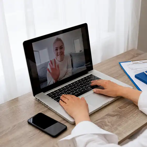Therapist conducting a virtual counseling session on a laptop with a smiling client.