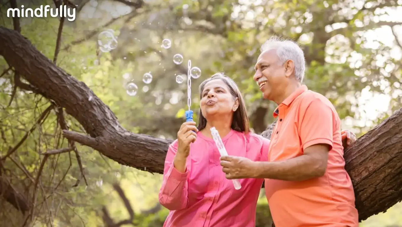 Senior couple joyfully playing with soap bubbles in a sunny park