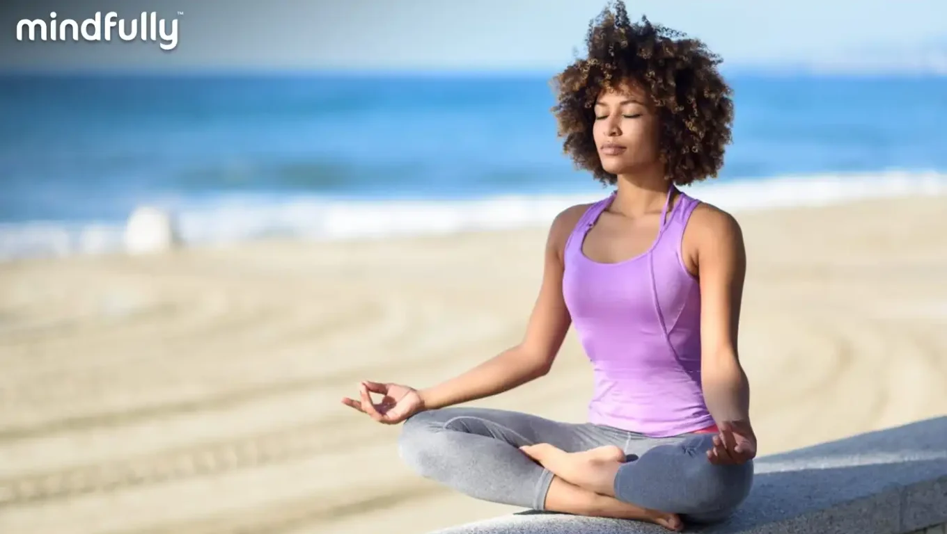 A woman sits cross-legged on the beach