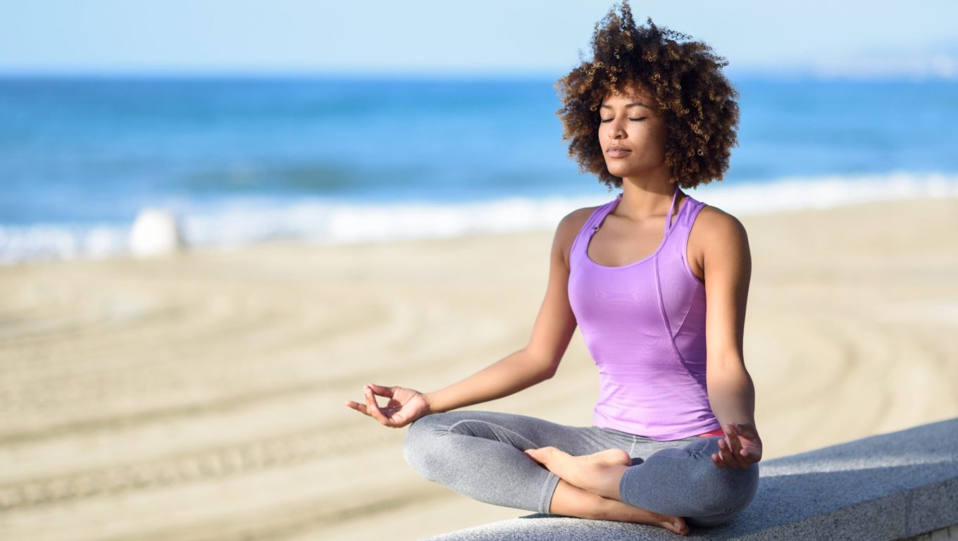 A woman sits cross-legged on the beach