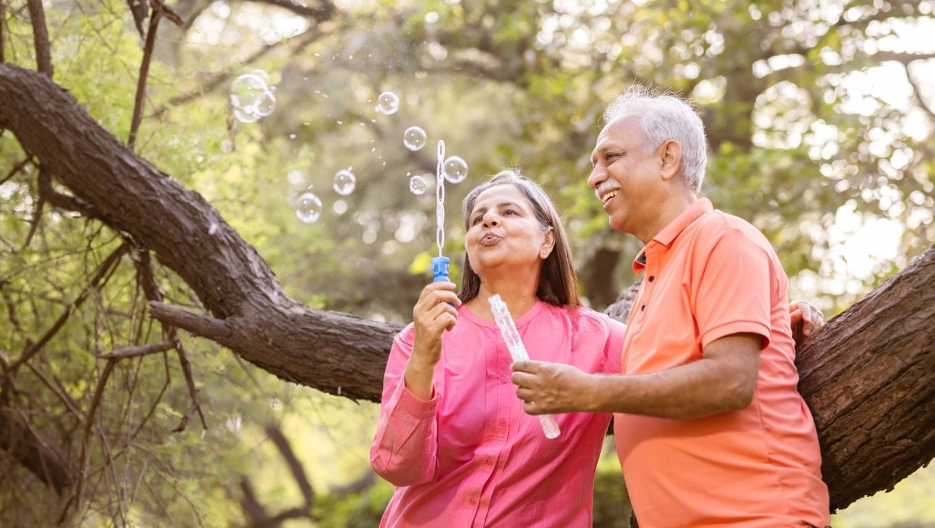 Senior couple joyfully playing with soap bubbles in a sunny park
