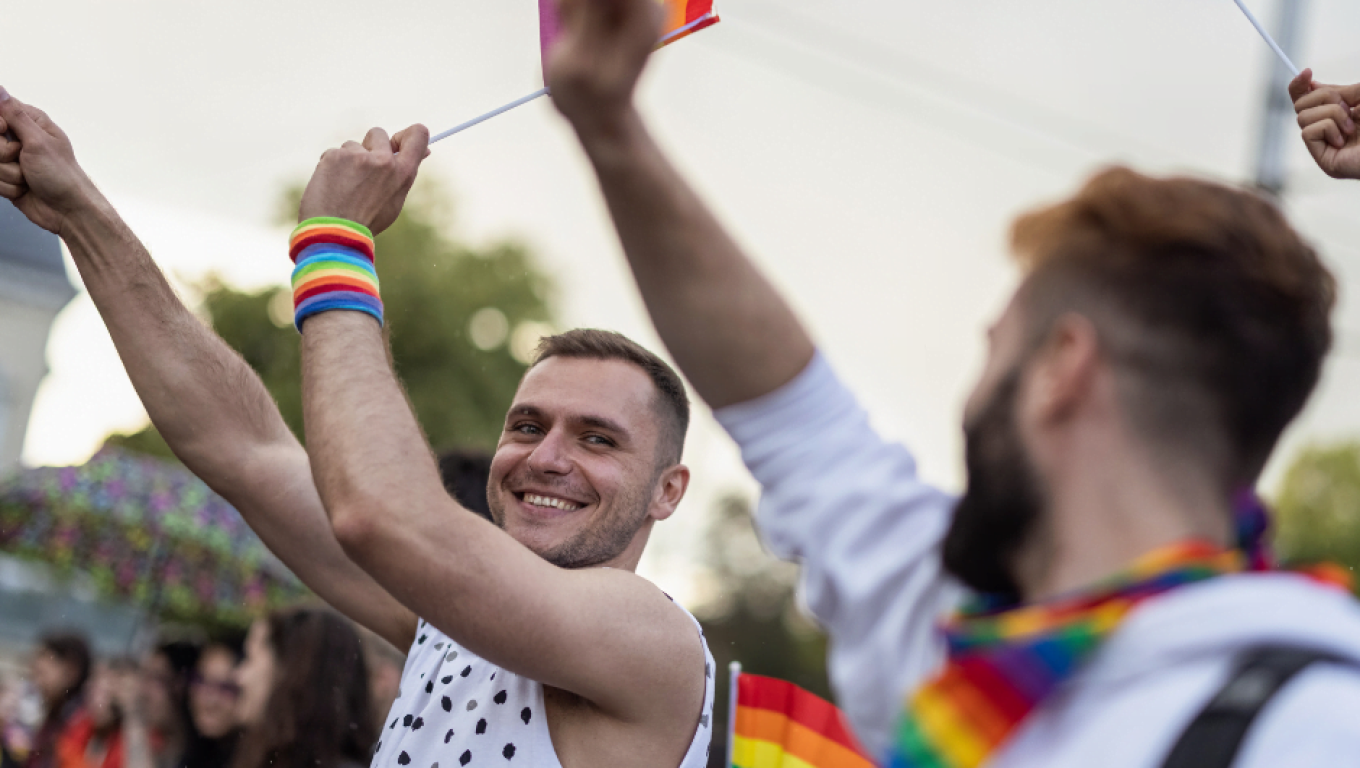 A group of men proudly holding vibrant rainbow flags