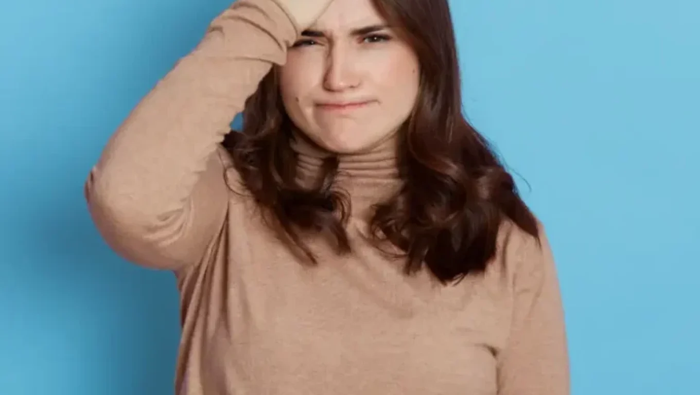 A woman showing frustration with herself, representing a moment of self-judgment that can be met with mindfulness.
