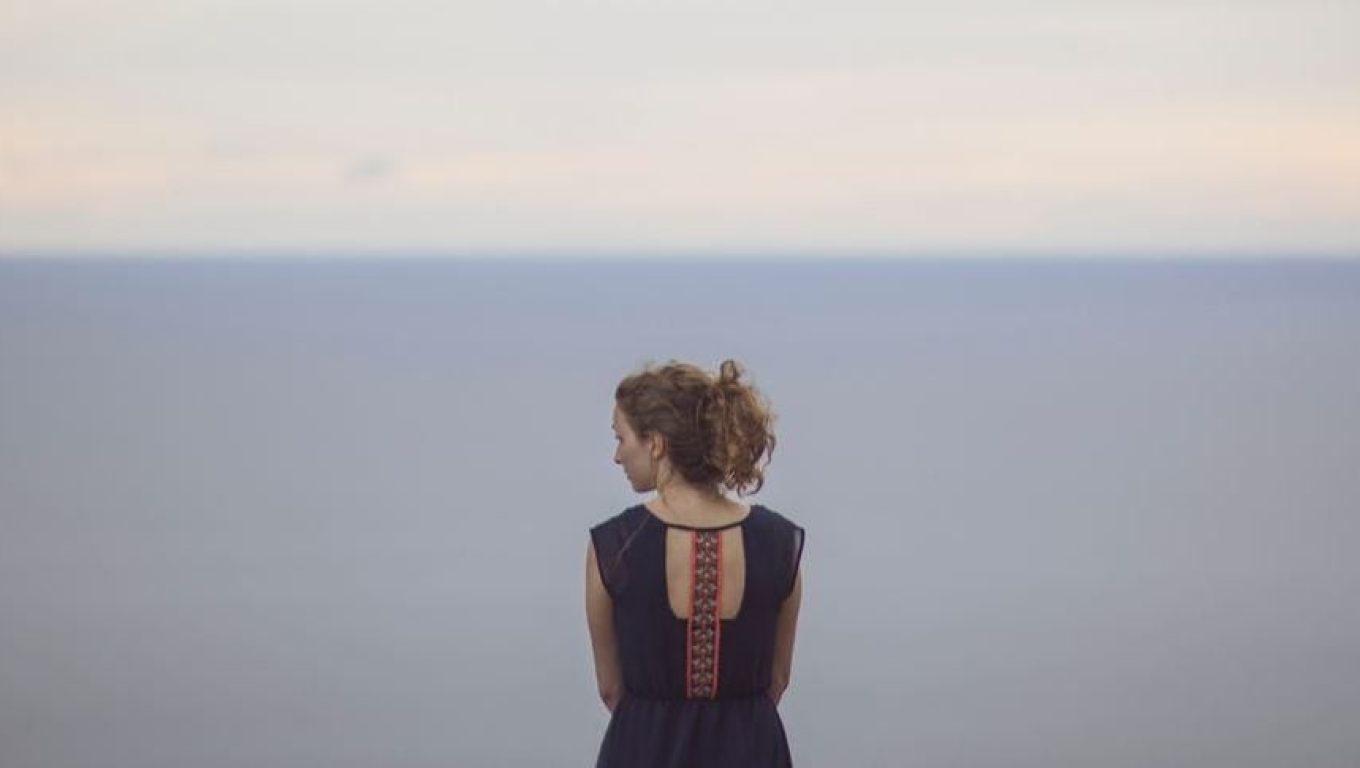 A woman stands on a cliff