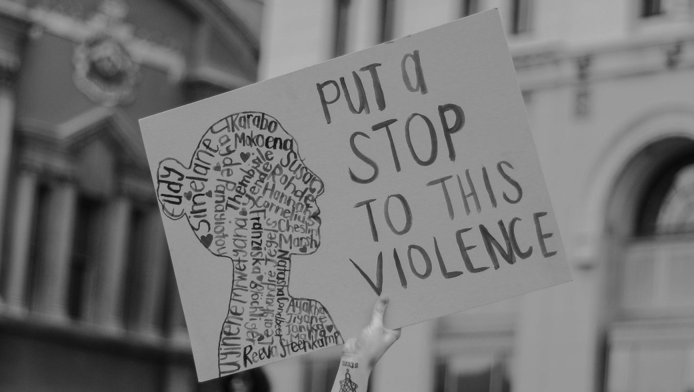 A woman holds a sign reading "Put a stop to this violence