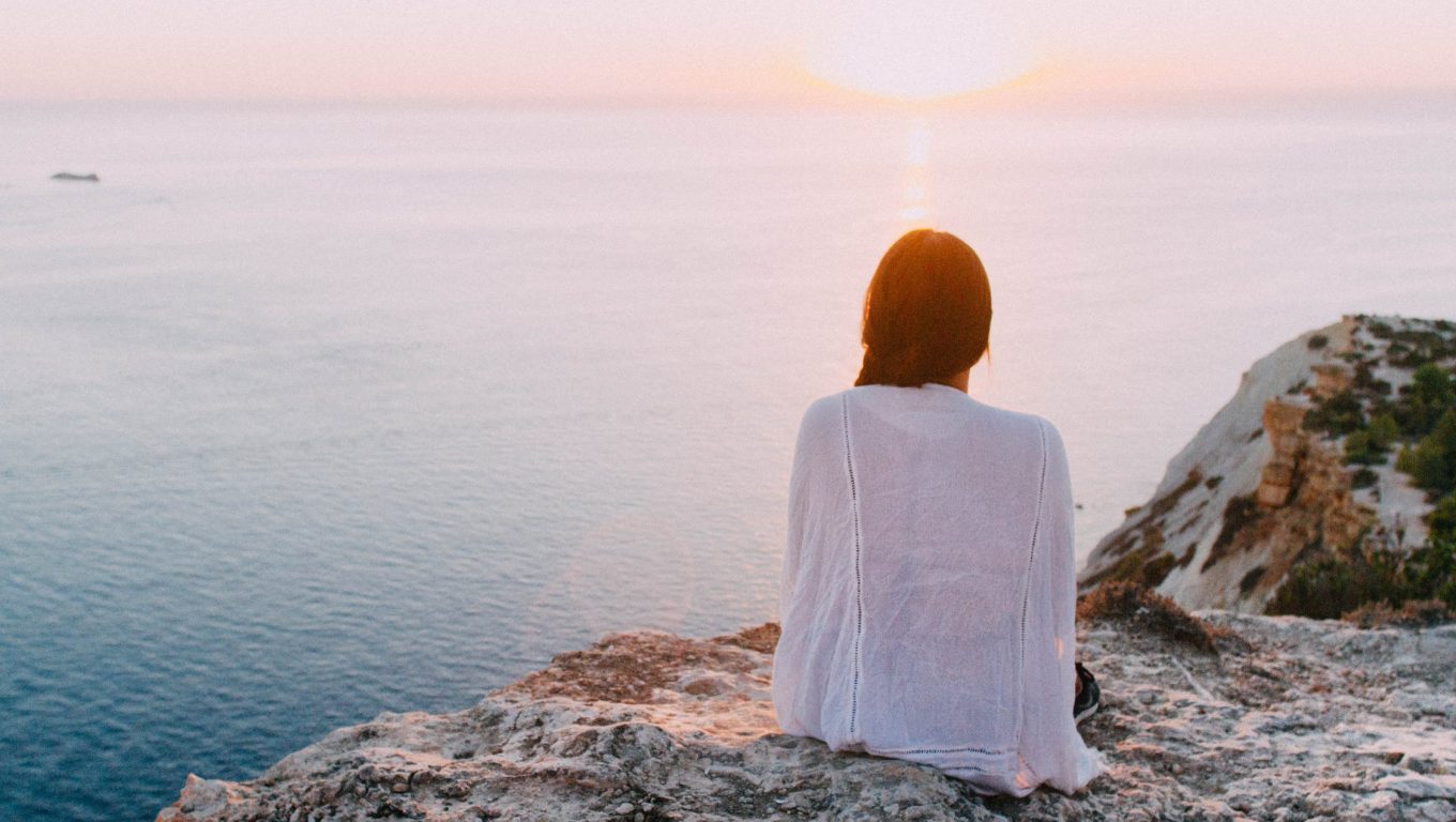 A woman sits on a rock