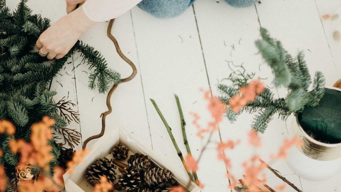 A woman carefully arranges a festive Christmas wreath on the floor
