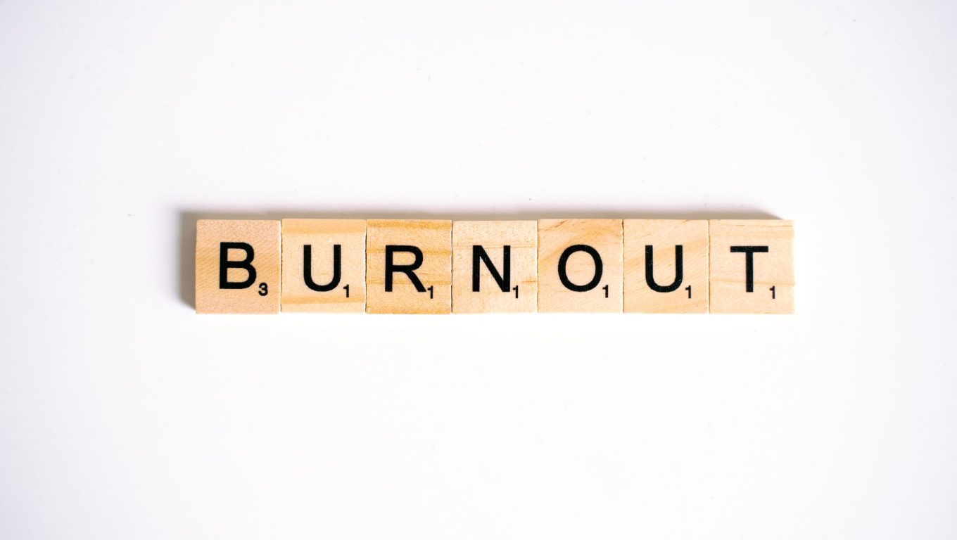 Scrabble tiles spelling the word "burnout" arranged on a wooden game board.