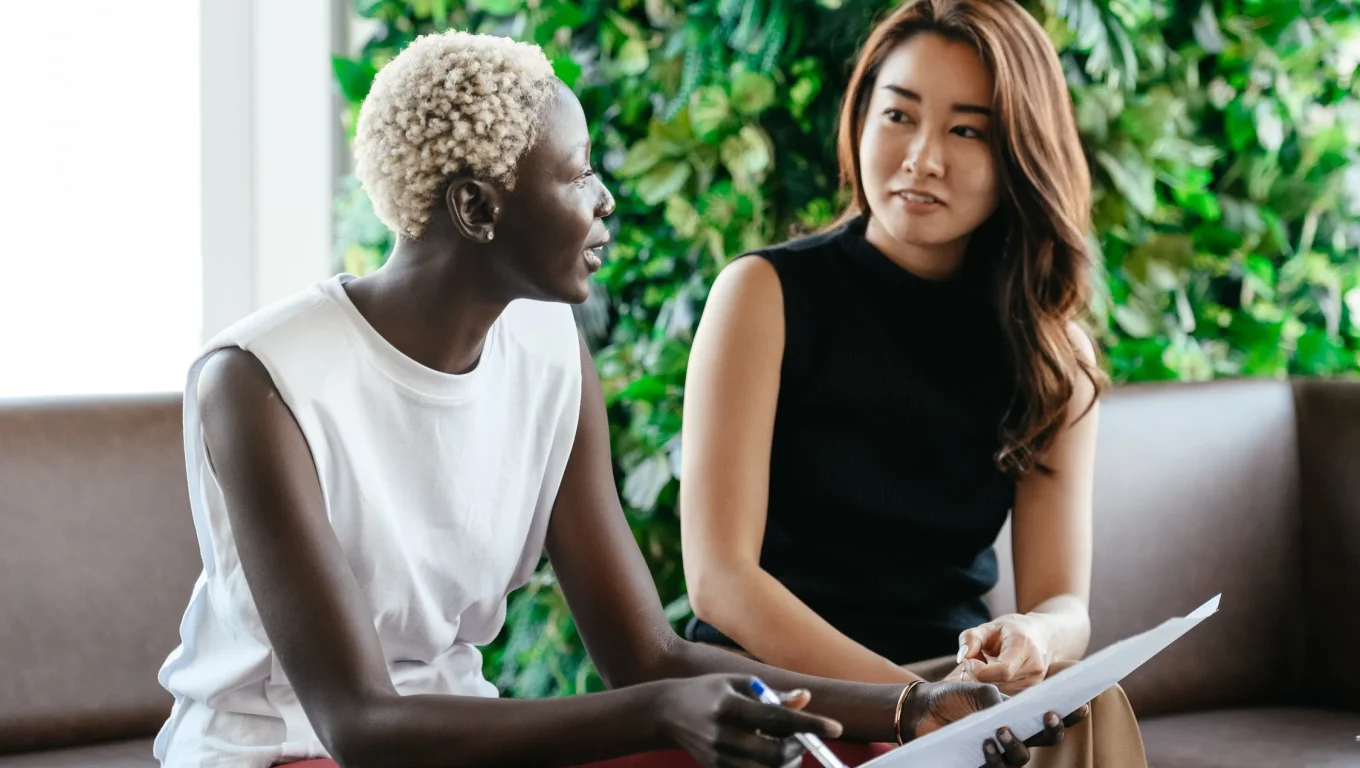 Two women sitting on a couch discussing job search strategies