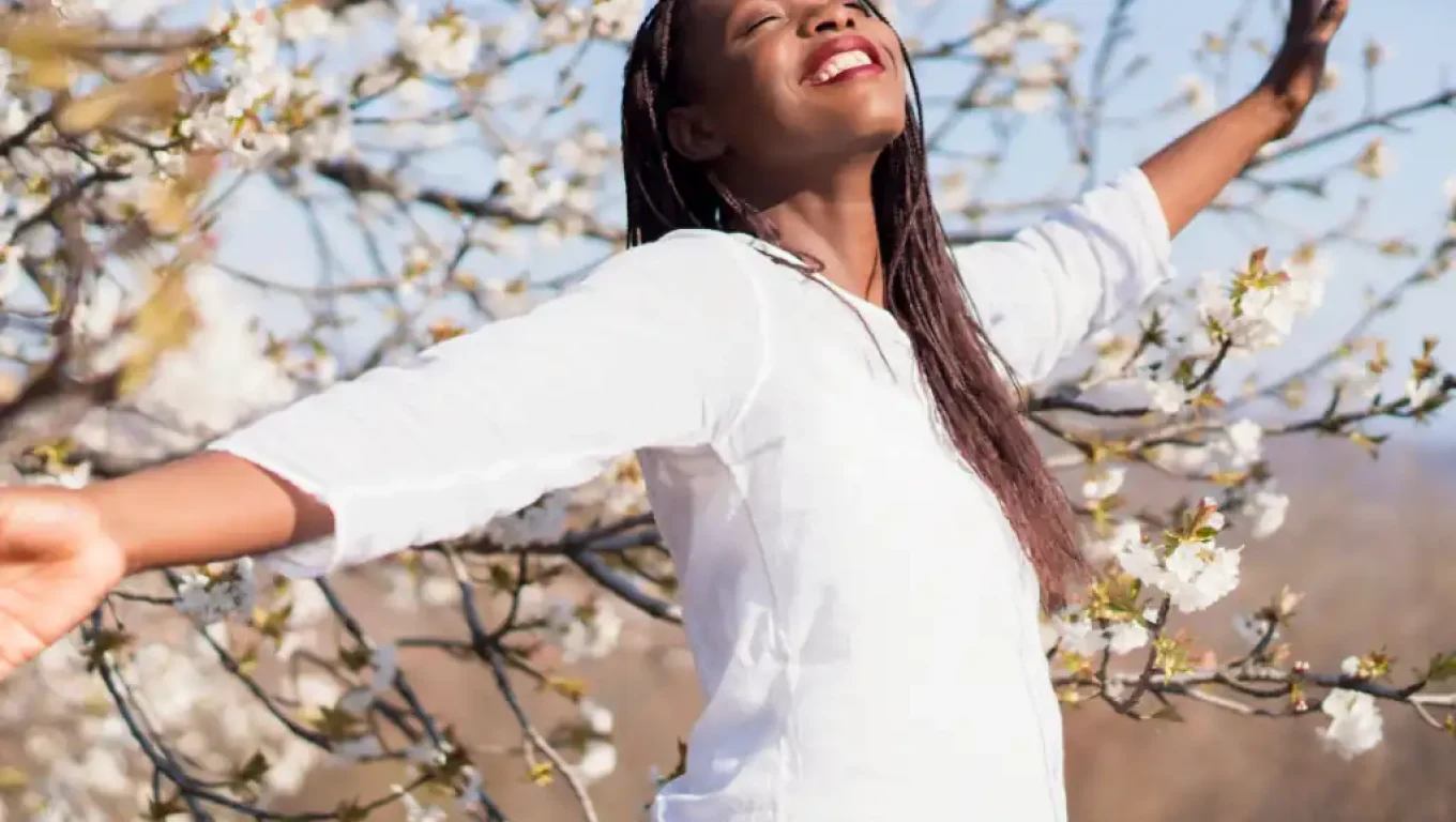 A woman poses in front of a flowering tree