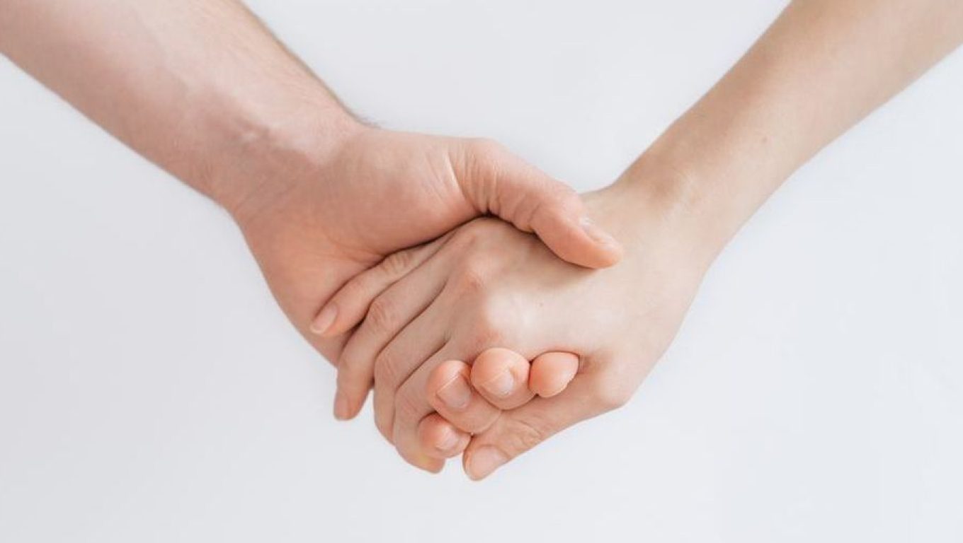 A couple holding hands against a plain white background